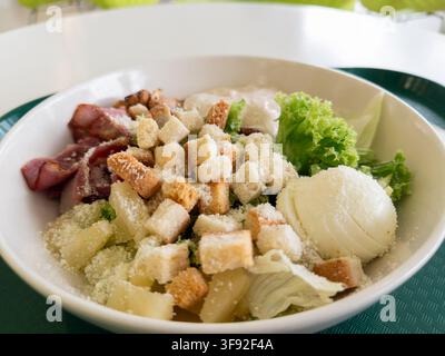 Appetizing Caesar salad featuring greens, savory meat and golden bread cubes served in a bowl, representing a delicious balanced meal choice for casua Stock Photo
