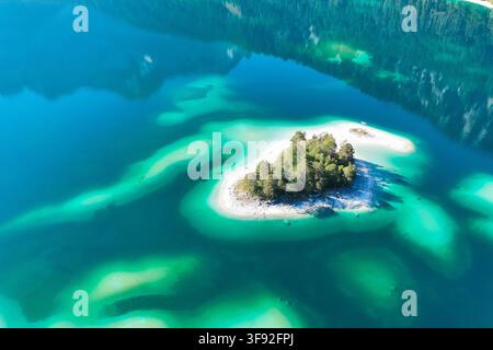 Wetterfeature, Morgenstille am Eibsee: Unterhalb der Zugspitze liegt der See bei Grainau nahe Garmisch-Partenkirchen in den frühen Stunden noch ruhig und nahezu unberührt. Doch an heißen Sommertagen ändert sich das Bild häufig schon ab Mittag. Dann strömen zahlreiche Ausflügler und Urlauber an den durch soziale Medien weltweit bekannt gewordenen Bergsee. Der zunehmende Massentourismus sorgt regelmäßig für einen regelrechten Besucheransturm. Unter dem hohen Verkehrsaufkommen, zugeparkten Straßen und dem großen Andrang leiden zunehmend auch die Anwohner in Grainau und rund um den Eibsee. Aufnahm Stock Photo