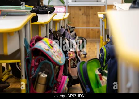 Kyiv, Ukraine - March 20, 2026: Varied student bags suspended from modern wooden desks inside a quiet school room, representing daily school life and Stock Photo