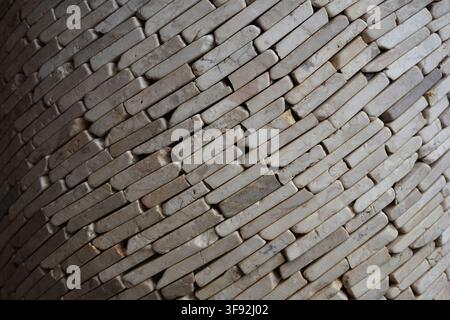 Horizontal texture background showing small off-white marble stone strips stacked diagonally to create a dynamic wall pattern. The natural stone. Stock Photo