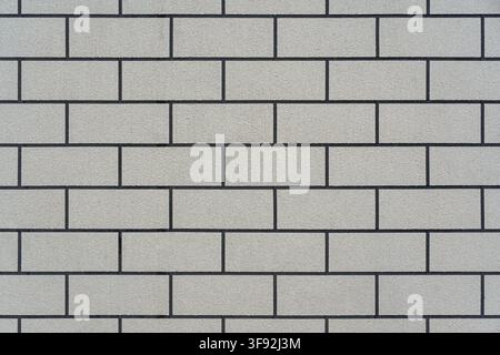 Full frame texture background featuring a clean, seamless running bond pattern of rectangular off-white or beige textured stone blocks. Stock Photo
