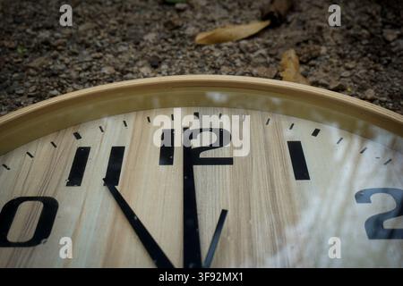 A Close-Up View of a Wooden Clock Face Resting on the Earthy Ground Stock Photo