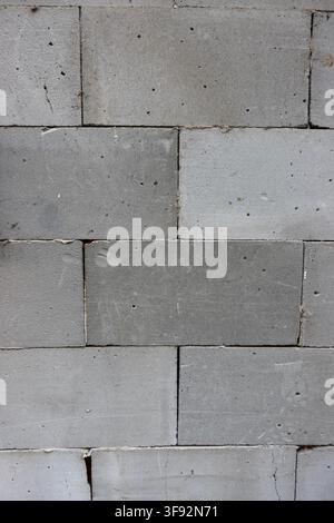 Close-up of an unfinished gray concrete block wall with visible mortar joints, pores and rough surface texture, useful as an industrial background Stock Photo