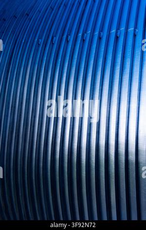 close-up of blue-toned metal bars with brushed surfaces, repeating parallel ridges and strong diagonal perspective Stock Photo