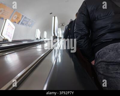 Kyiv, Ukraine - March 16, 2026: Commuters standing on a moving staircase in an underground transit hub, illustrating modern urban lifestyle and the fl Stock Photo