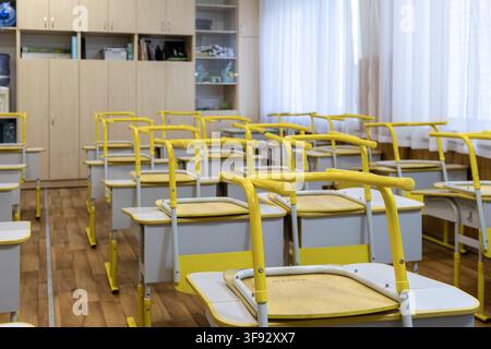 Rows of classroom furniture with flipped chairs positioned on desks in a clean learning environment, creating an orderly atmosphere during semester in Stock Photo