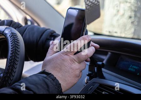 A close-up view of hands placing a mobile phone into a vehicle holder on the dashboard, emphasizing safety and ease of access to digital tools while d Stock Photo
