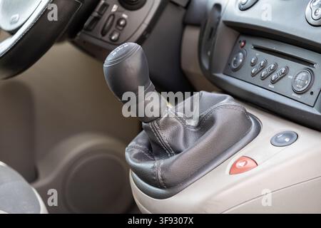 A close view of a manual transmission stick inside an automobile cabin features textured black materials and central buttons that emphasize automotive Stock Photo