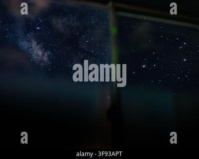 Milky Way and starry night sky seen through a guesthouse window in Kozushima Island, Tokyo, Japan Stock Photo