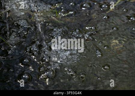 Close-up of Water Splashing with Air Bubbles and Foam on Dark Water Surface Stock Photo