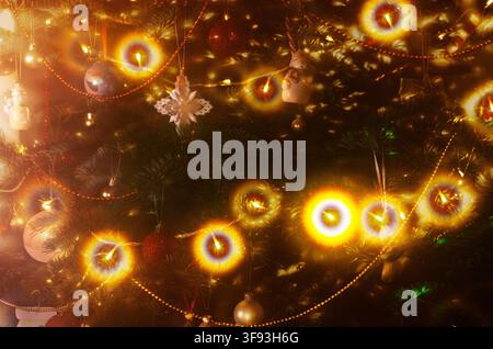 A closeup shot captures the enchanting glow of a decorated Christmas tree, adorned with various ornaments and bright, warm lights Stock Photo