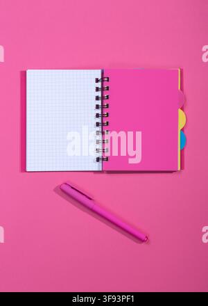 Notepad with a pink ballpoint pen on a pink background Stock Photo