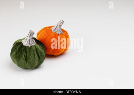 A horizontal shot of two ornamental pumpkins made from plush velvet fabric in dark green and bright orange. The arrangement focuses on the contrast be Stock Photo