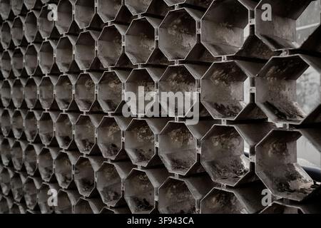 A perspective shot of a repeating hexagonal pattern grid wall structure, showing dark geometric metal cutouts and textured depth suitable for backgrou Stock Photo