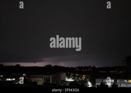 A lightning bolt is striking from dark clouds at a night cityscape. Stock Photo
