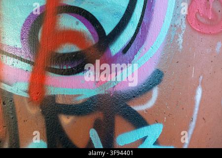 Colorful abstract graffiti art is spray-painted on a textured concrete wall in an urban environment. Stock Photo