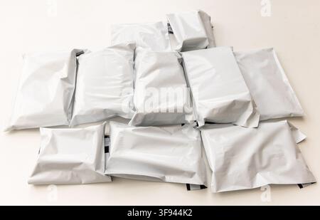 Many unbranded white shipping envelopes are stacked on a light surface Stock Photo