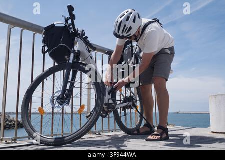 Cyclist Locking His Bicycle to a Metal Railing for Security Stock Photo