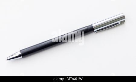 A black and silver pen rests on a plain white surface Stock Photo