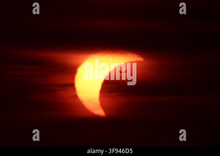 RECORD DATE NOT STATED Partial solar eclipse at sunset with an airplane silhouette transit ROME, ITALY - AUGUST 12, 2026: Silhouette of a commercial airplane flying across the crescent sun during a partial solar eclipse at sunset, framed by dark atmospheric clouds. Rome RM Italy Copyright: xGennaroxLeonardix Stock Photo