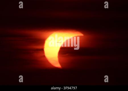 August 13, 2026, Rome, Rm, Italy: Silhouette of a commercial airplane flying across the crescent sun during a partial solar eclipse at sunset, framed by dark atmospheric clouds. (Credit Image: © Gennaro Leonardi/ZUMA Press Wire) EDITORIAL USAGE ONLY! Not for Commercial USAGE! Stock Photo