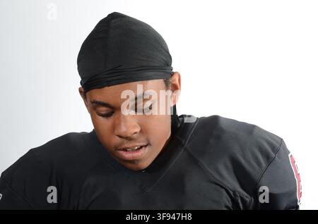Young Black American football player in a plain black jersey numbered 87, photographed against a white studio background. Stock Photo