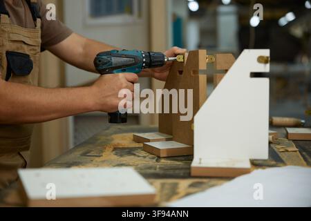 Dedicated craftsman meticulously aligning and securing wood pieces in busy workshop environment Stock Photo