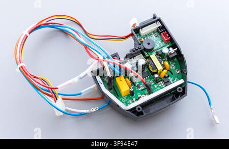 A colorful electronic circuit board with wires lies on a grey surface Stock Photo