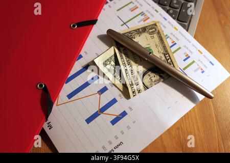 Financial document featuring charts and graphs, with us dollar banknotes and a fountain pen placed on top, illustrating business planning, investment, Stock Photo
