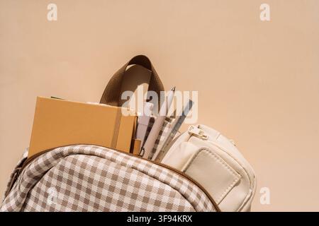 School backpack filled with notebooks, pens and pencil case in warm sunlight Stock Photo