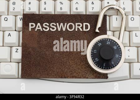 Password text on a rusty sign with combination lock on a white computer keyboard for old and weak authentication Stock Photo