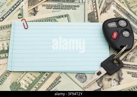 Blank lined index cards with car keys on twenty dollar bills for the cost of owning a car Stock Photo