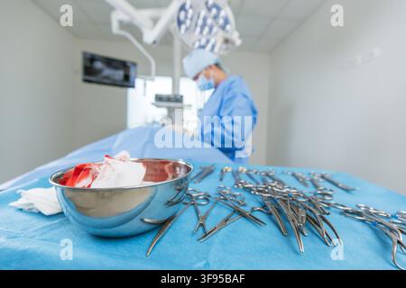 A female surgeon is focused on her work in a hospital during a surgical procedure with tools arranged on the table. Stock Photo