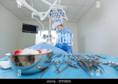 Surgeon in modern hospital operating room performs surgery with a team on a patient using sterile instruments. Stock Photo