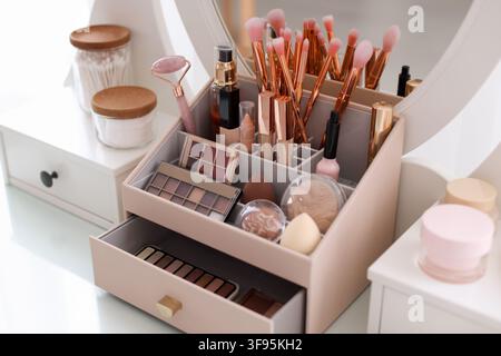 Organizer with different makeup products and brushes on vanity indoors, closeup Stock Photo