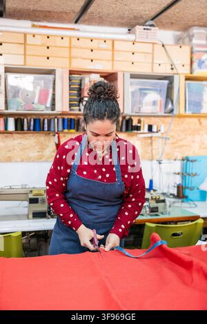 Artisan woman cutting fabric for upholstery in workshop Stock Photo