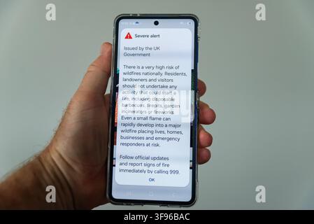 Severe alert for wildfires on mobile phone. The UK government has issued a severe alert for a high risk of wildfires due to the spell of dry weather Stock Photo