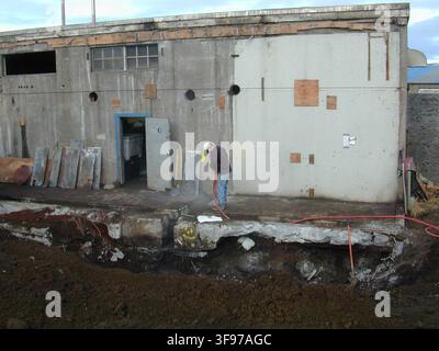 A worker uses a jackhammer to break up the concrete floor of the decommissioned power plant on St. Paul Island, Alaska, as part of the Pribilof Islands Restoration Project, in a photograph taken on November 7, 2002. Stock Photo