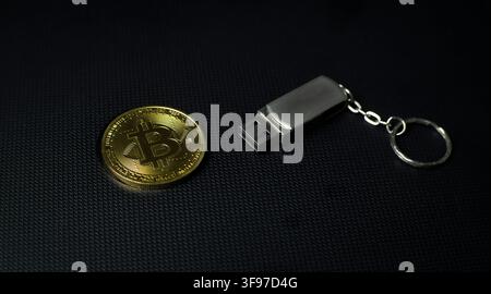 Bitcoin coin beside a USB flash drive on a dark surface, representing crypto wallet, digital storage, backup, security, privacy Stock Photo