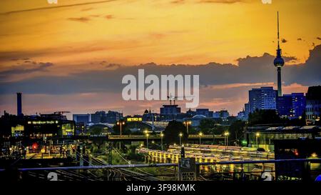 View of railway tracks from Modersohn Bridge, skyline at sunset with television tower and illuminated buildings in the foreground, Friedrichshain, Ber Stock Photo