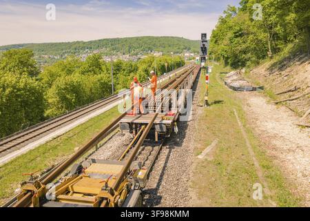 Worker on a rail maintenance platform in a rural area with forest and sky, Leonhard Weiss construction site for the renovation of the railway station Stock Photo