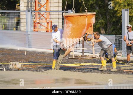 Two construction workers empty concrete from a large container on a construction site, Parkhausbau, Calw, Germany Stock Photo