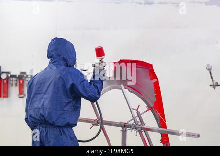 Person wearing protective clothing paints a vehicle part with red paint, Painter, Calw, Germany Stock Photo
