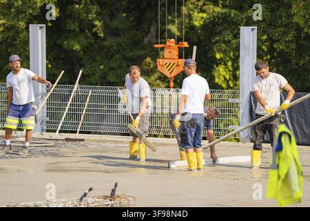 Four construction workers are smoothing concrete on a construction site, all wearing safety clothing, parking garage construction, Calw, Germany Stock Photo