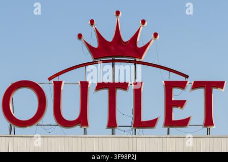 Outlet writing and Royal Crown red LED neon logo sign on building roof against blue sky Stock Photo