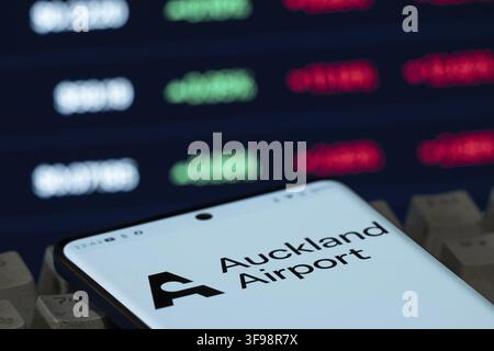 Auckland Airport logo on a smartphone screen with stock market figures in the background Stock Photo