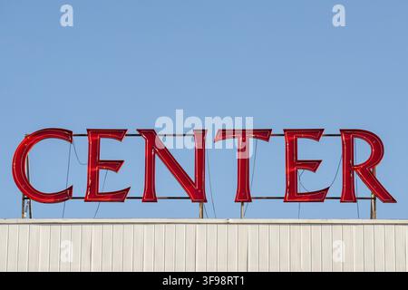 Luminous and vivid Center writing and red LED neon logo sign on building roof against blue sky Stock Photo