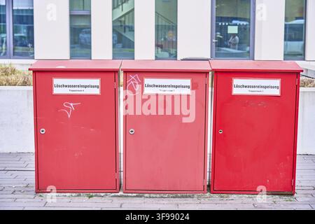 Three red storage boxes stand next to each other on an urban street, Potsdam near the main train station, Brandenburg, Germany Stock Photo
