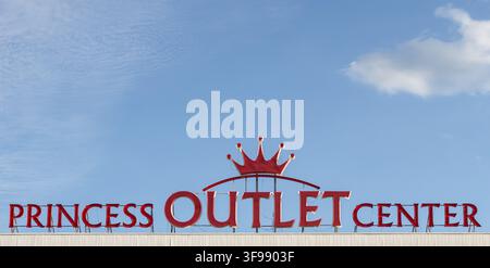 Luminous and vivid writing and red LED neon logo sign for the Princess Outlet Center on building roof against blue sky in Sofia Bulgaria Stock Photo