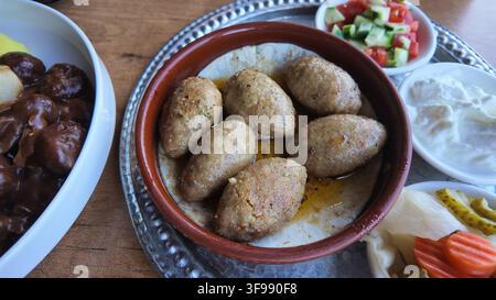 Middle Eastern Kibbeh Mezze Platter With Spiced Meatballs, Yogurt Sauce, Pickles and Vegetable Salad Stock Photo